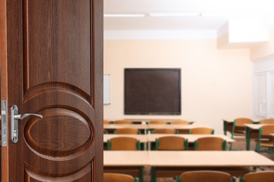 Wooden door open into modern empty classroom