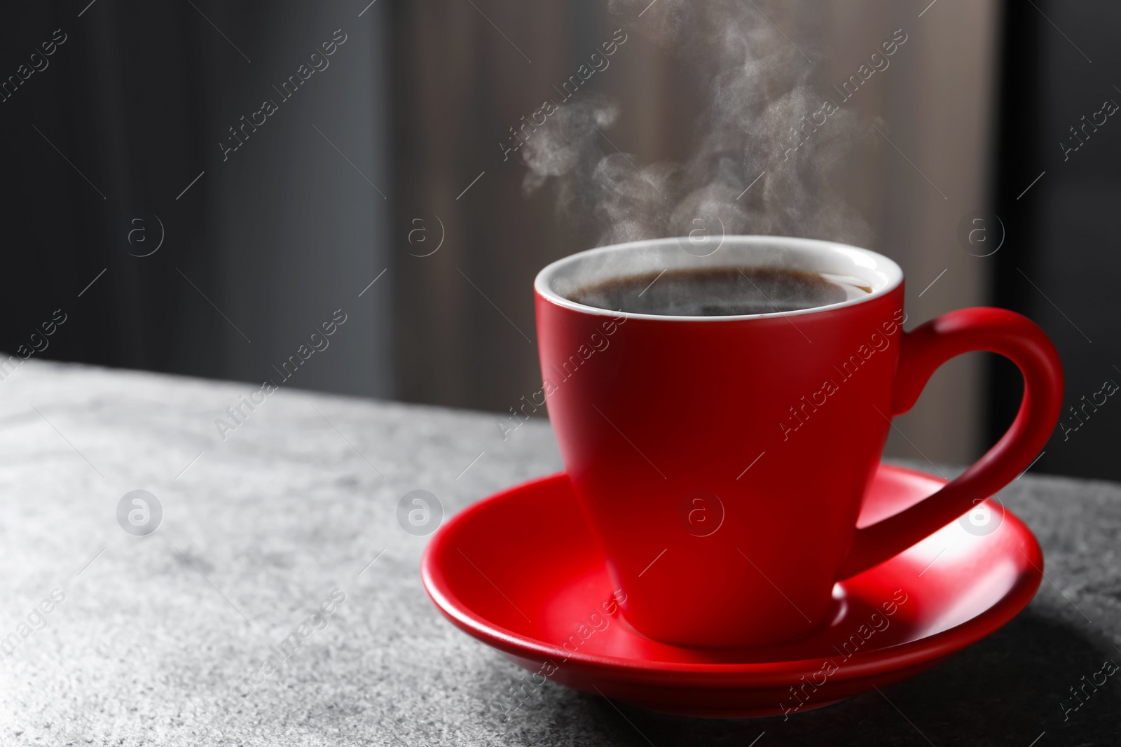 Image of Red cup with hot steaming coffee on grey table indoors, space for text