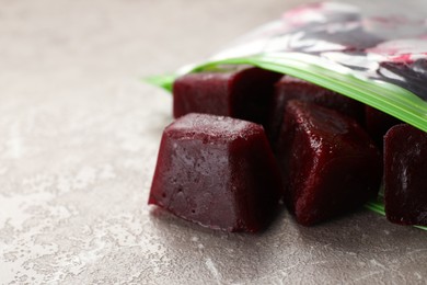Photo of Frozen beet puree cubes in plastic bag on marble table, closeup. Space for text