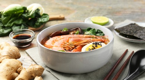 Delicious ramen with shrimps and egg in bowl served on table, closeup. Noodle soup