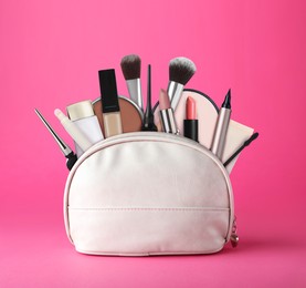 Image of Cosmetic bag filled with makeup products on pink background