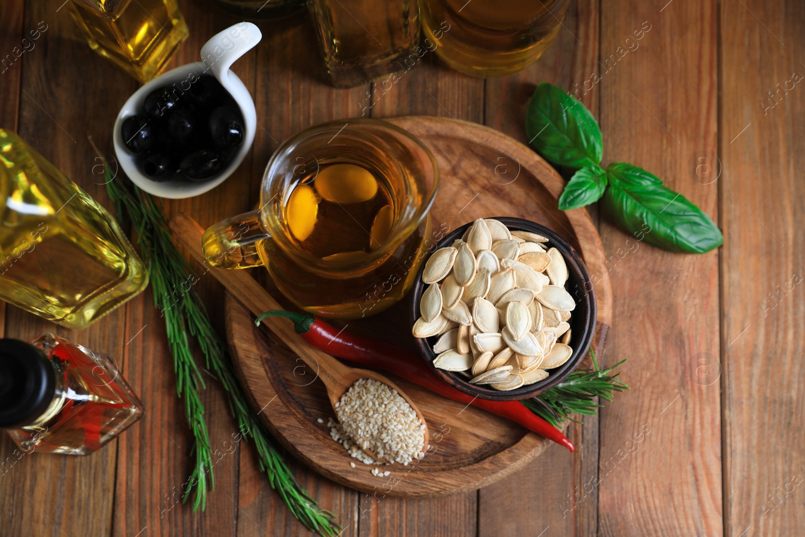 Photo of Different cooking oils and ingredients on wooden table, flat lay