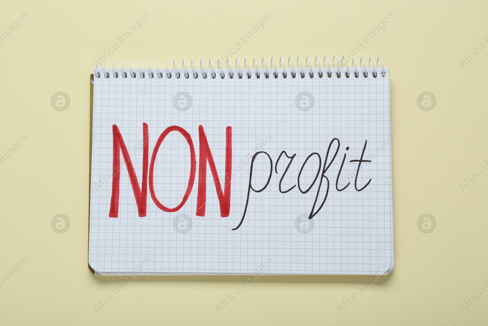 Photo of Notebook with phrase Non Profit on beige background, top view