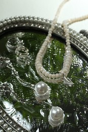 Photo of Elegant jewelry with water drops on vintage mirror, closeup