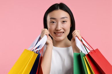 Photo of Happy woman with shopping bags on pink background