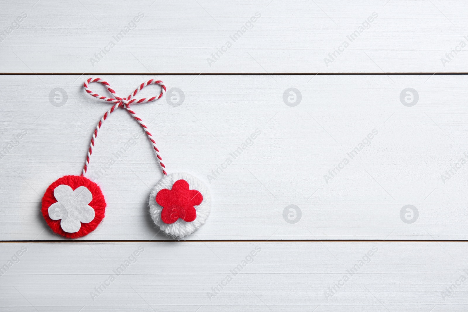 Photo of Traditional martisor on white wooden background, top view with space for text. Beginning of spring celebration