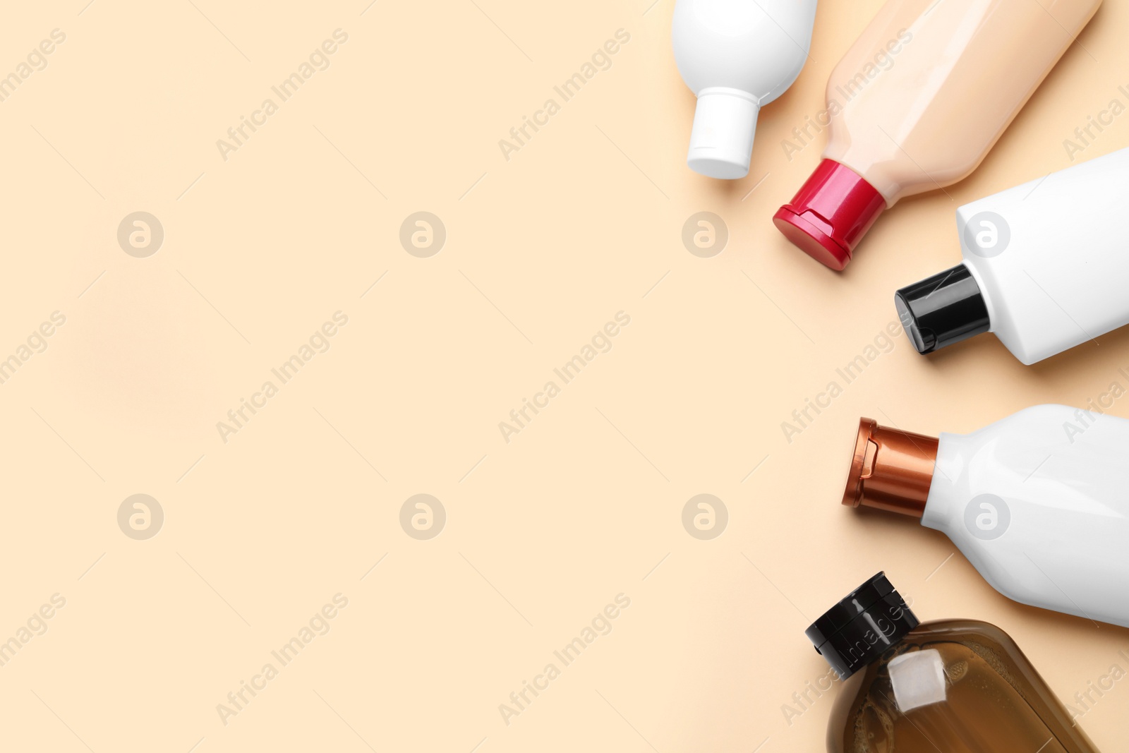 Photo of Bottles of shampoo on beige background, flat lay. Space for text