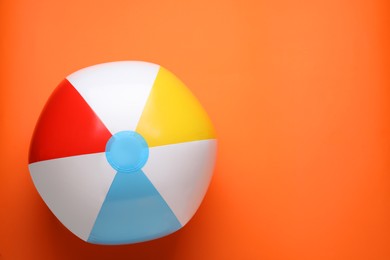 Photo of Bright beach ball on orange background, top view. Space for text