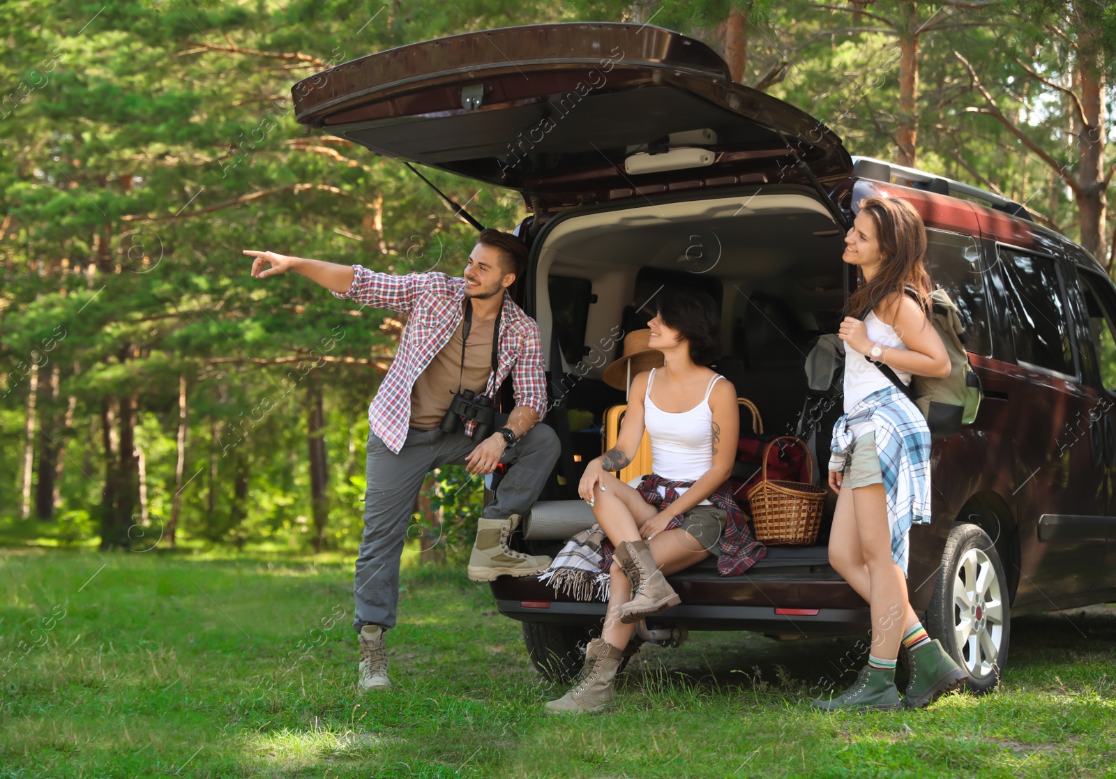 Photo of Young friends near van with camping gear in forest
