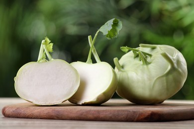 Photo of Whole and cut kohlrabi plants on wooden table
