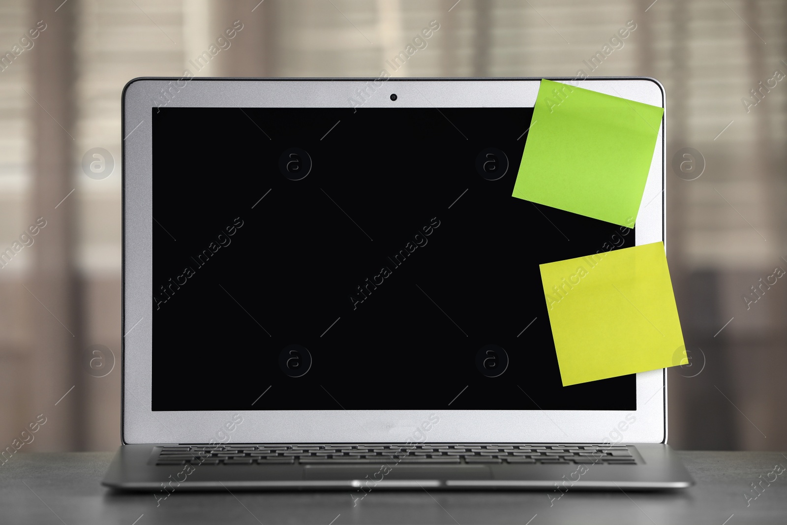 Photo of Laptop with blank sticky notes on grey office desk. Space for text