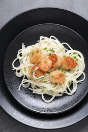 Delicious scallop pasta with green onion on grey table, top view