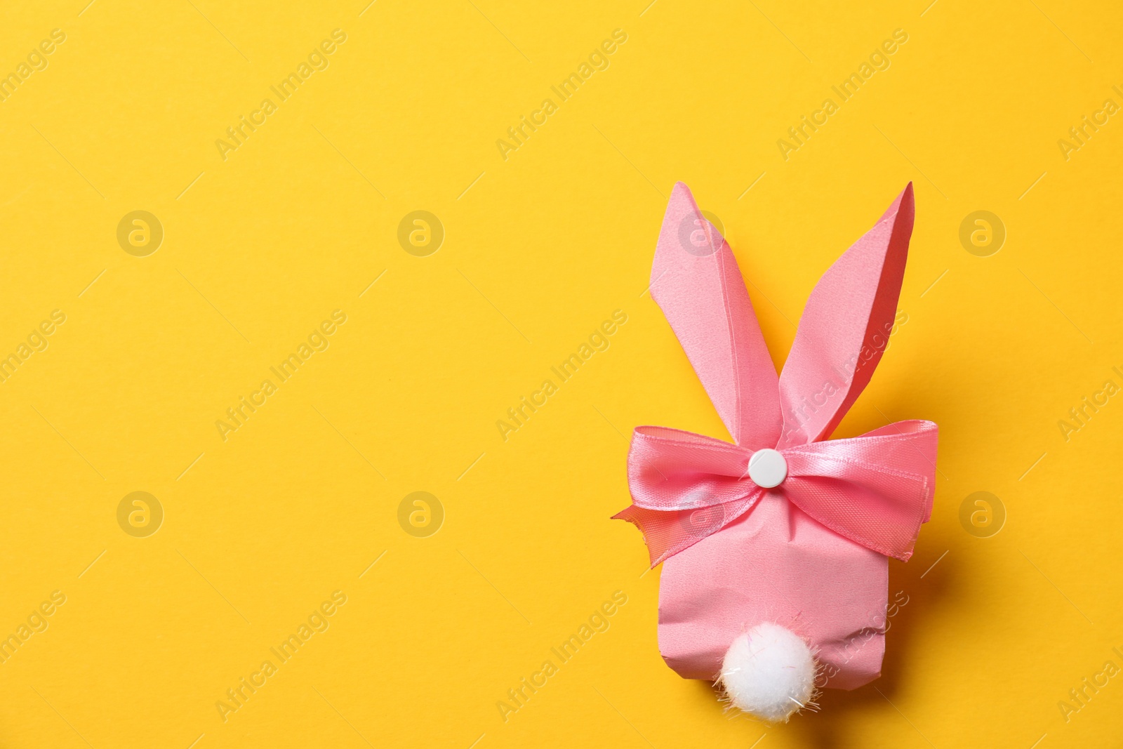 Photo of Creative Easter bunny gift bag on color background, top view with space for text