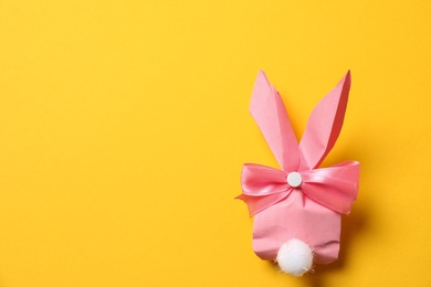 Photo of Creative Easter bunny gift bag on color background, top view with space for text