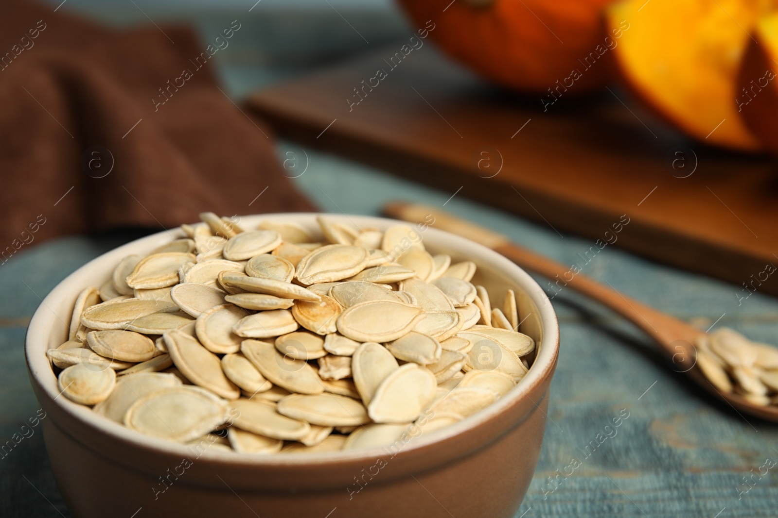 Photo of Bowl of raw pumpkin seeds on blue wooden table, closeup. Space for text