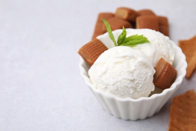 Photo of Scoops of tasty ice cream with mint and caramel candies on white table, closeup. Space for text