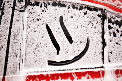 Photo of Foam with smiling face on vehicle side window. Car wash