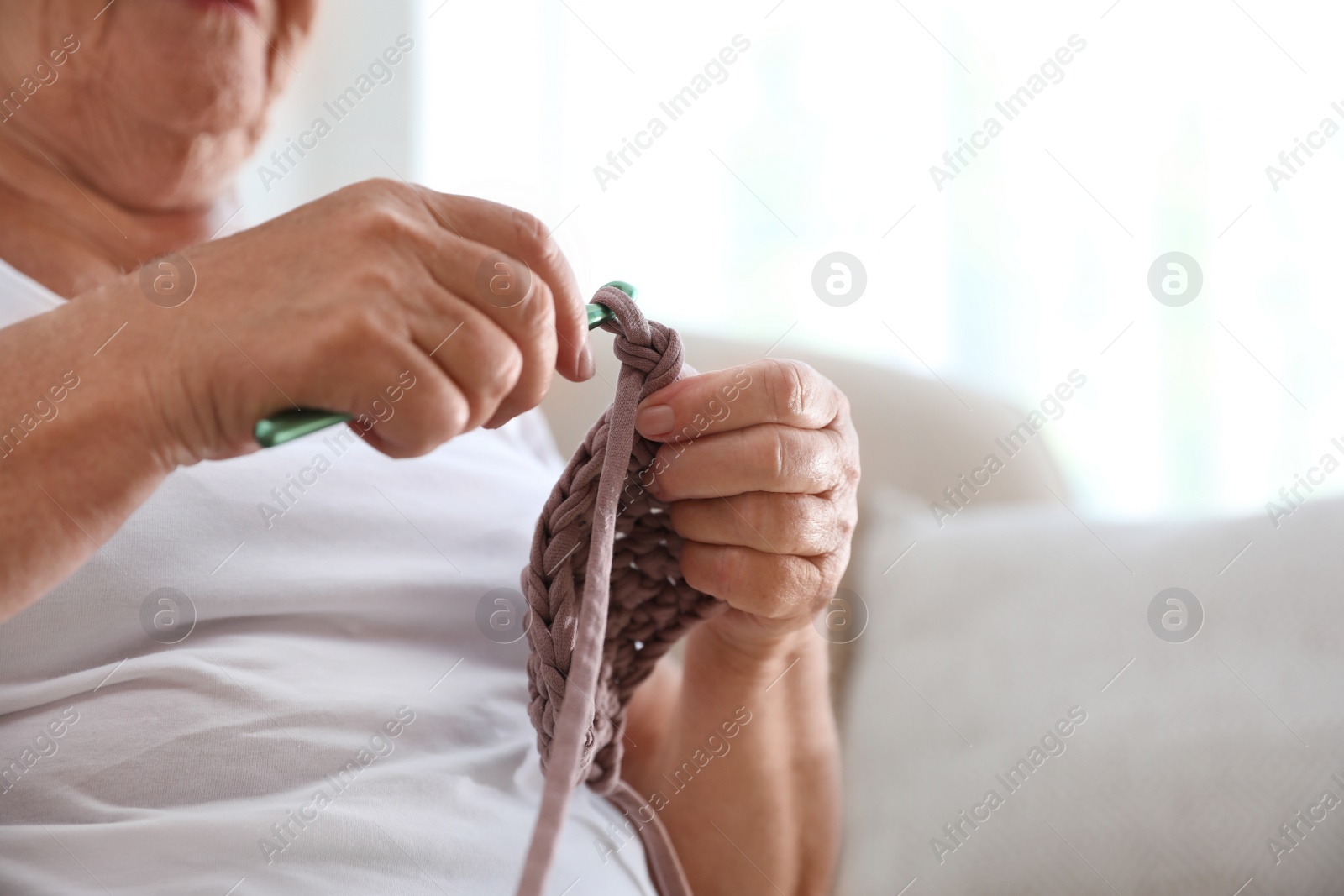 Photo of Elderly woman crocheting at home, closeup. Creative hobby