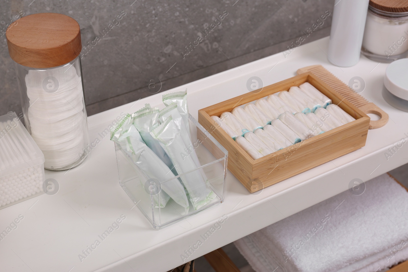 Photo of Many different tampons and personal care products on white table near grey wall