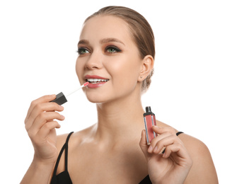 Photo of Beautiful woman applying lip gloss on white background. Stylish makeup