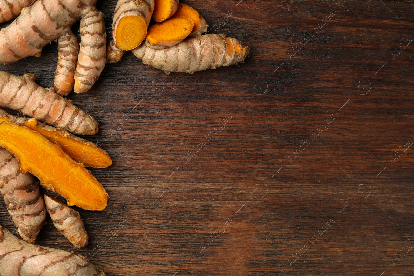 Photo of Many fresh turmeric roots on wooden table, flat lay. Space for text