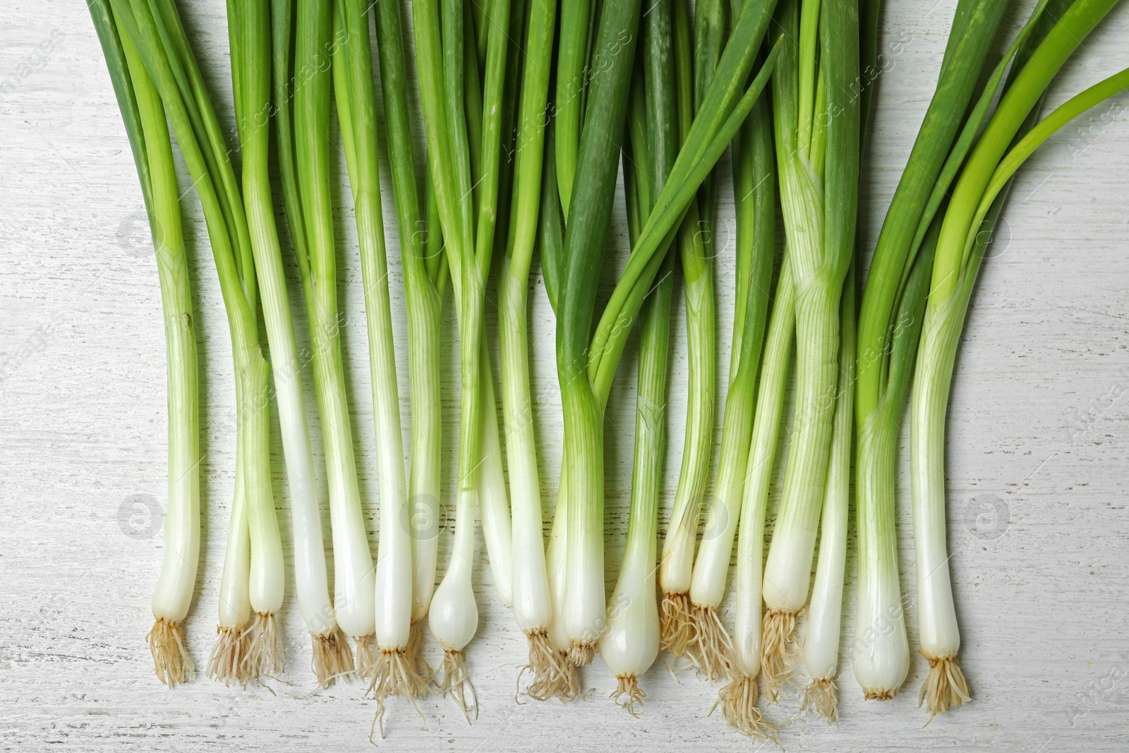 Photo of Fresh green onions on white wooden background, top view