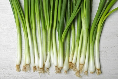 Photo of Fresh green onions on white wooden background, top view