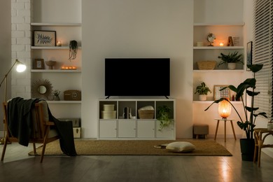 Stylish wide TV set on stand in room