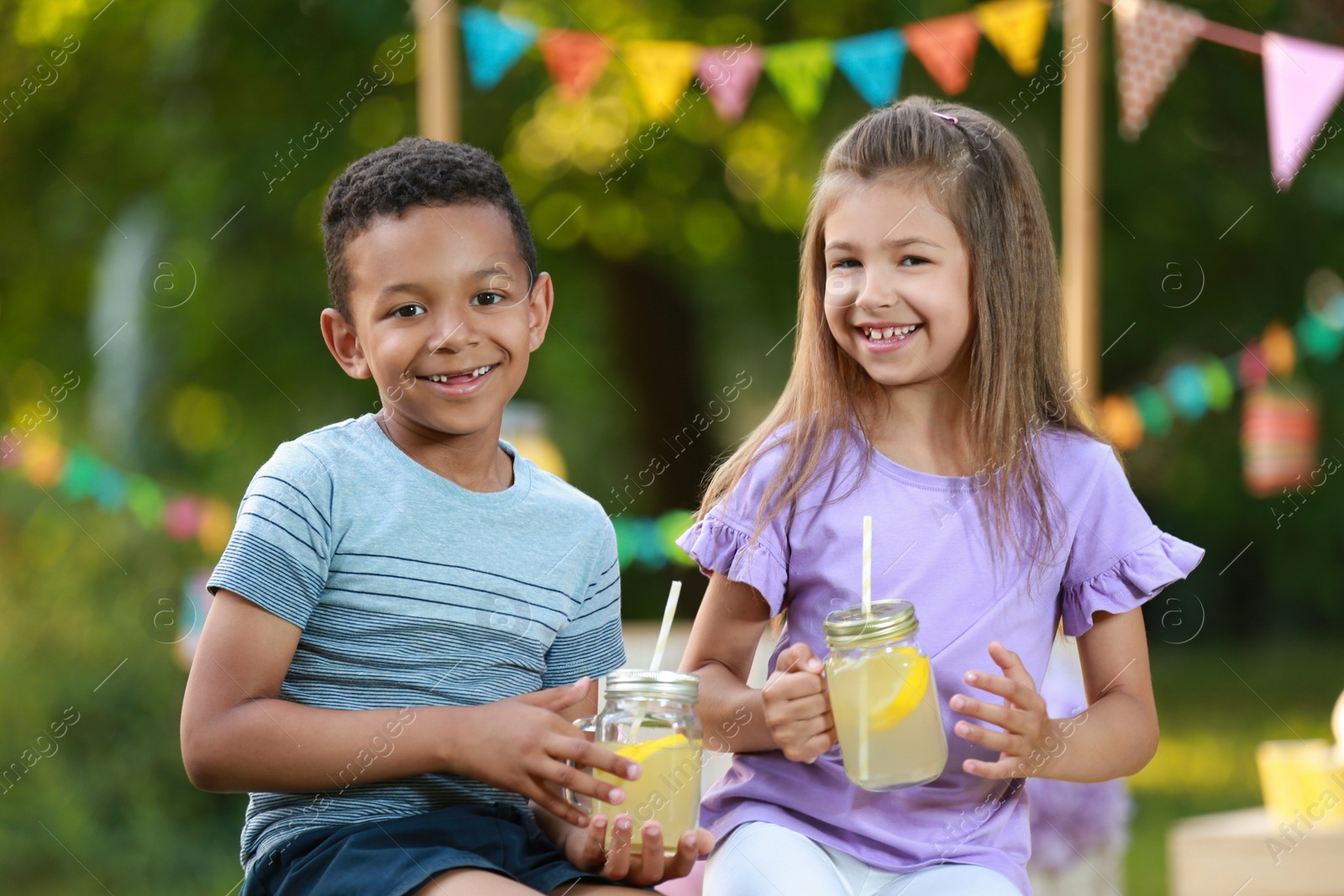 Photo of Cute little children with natural lemonade in park. Summer refreshing drink