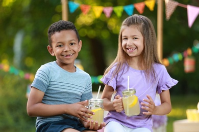 Cute little children with natural lemonade in park. Summer refreshing drink