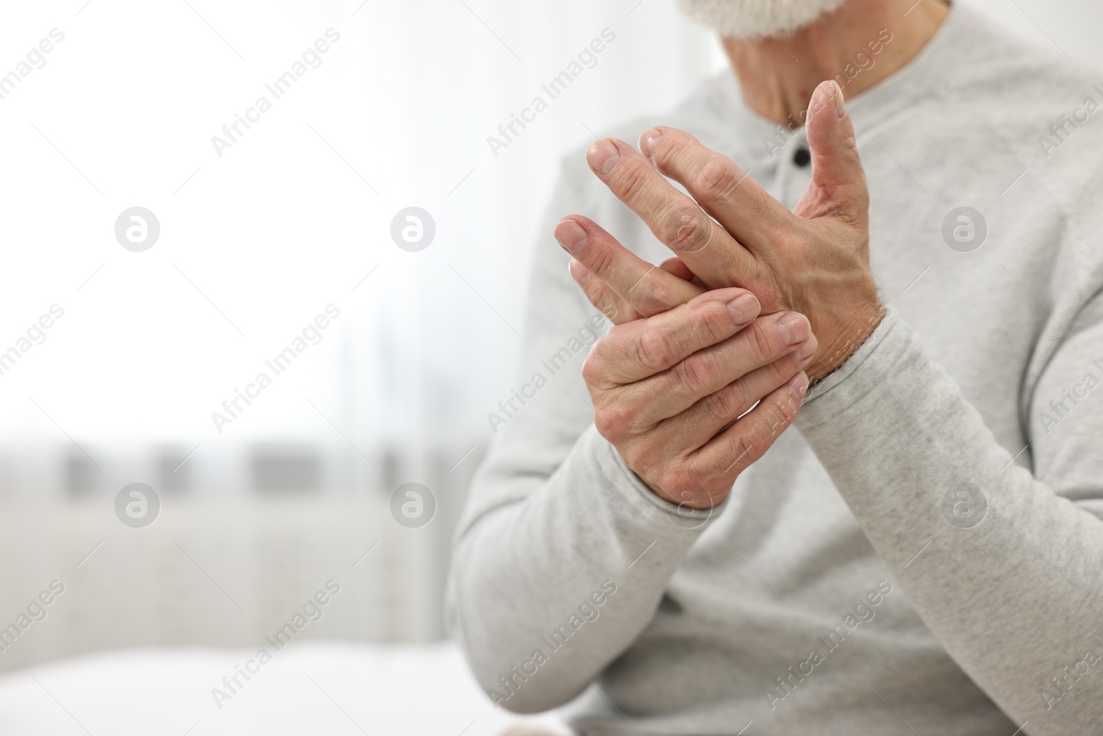 Photo of Arthritis symptoms. Man suffering from pain in hand at home, closeup. Space for text