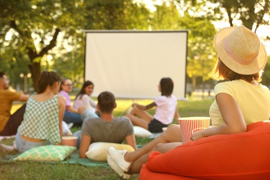 Photo of Young people with popcorn watching movie in open air cinema. Space for text