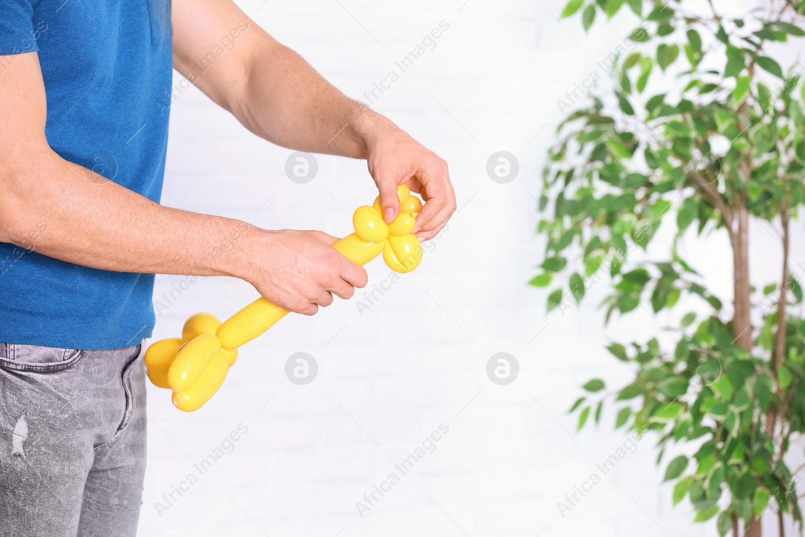 Photo of Man making balloon figure on blurred background, closeup. Space for text