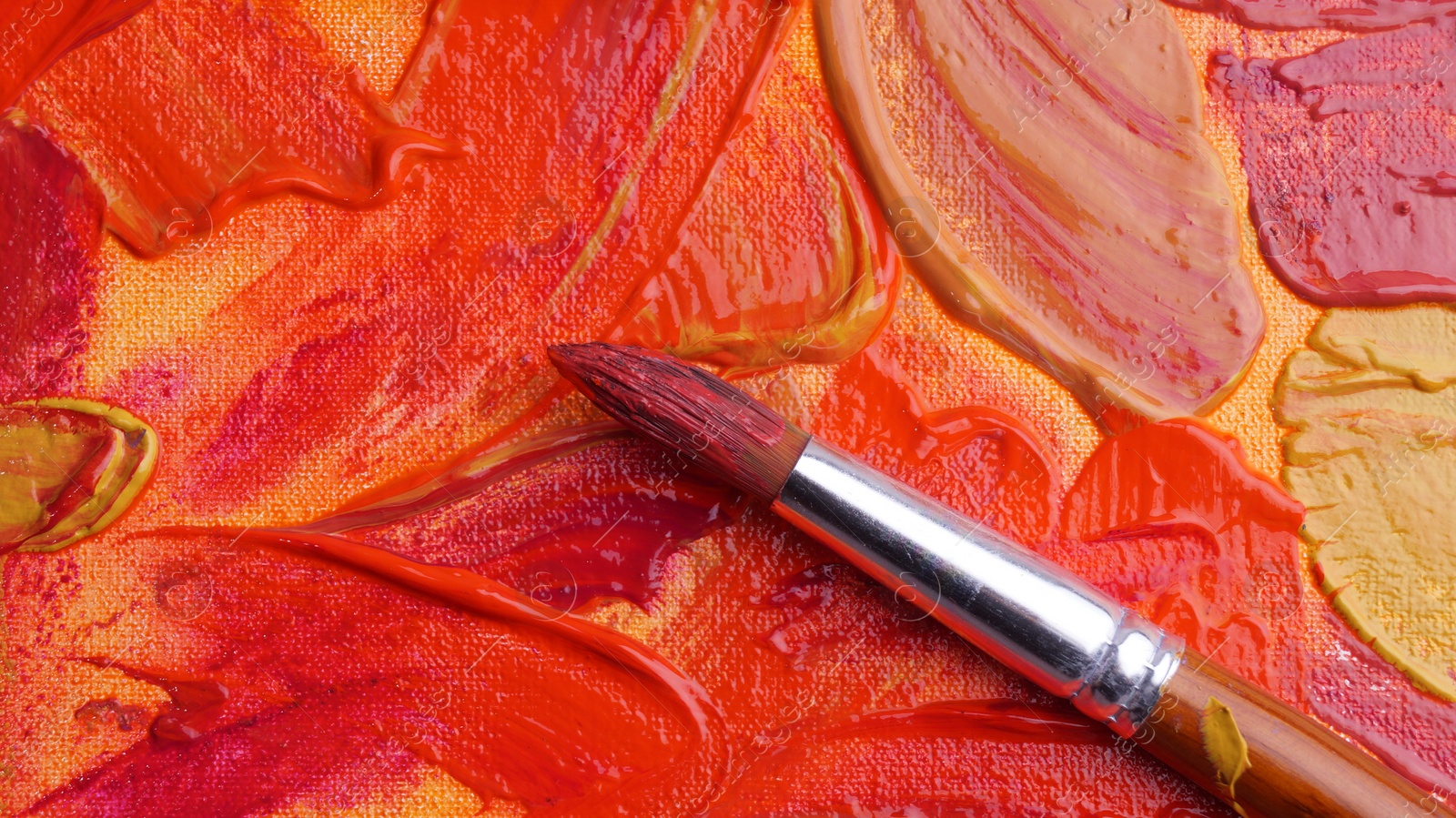 Photo of Brush on artist's palette with mixed paints, top view
