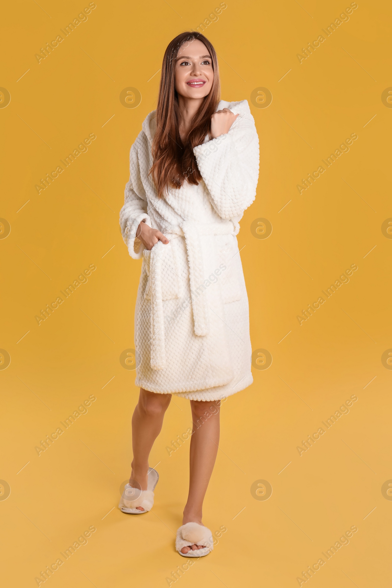 Photo of Beautiful young woman in bathrobe on yellow background