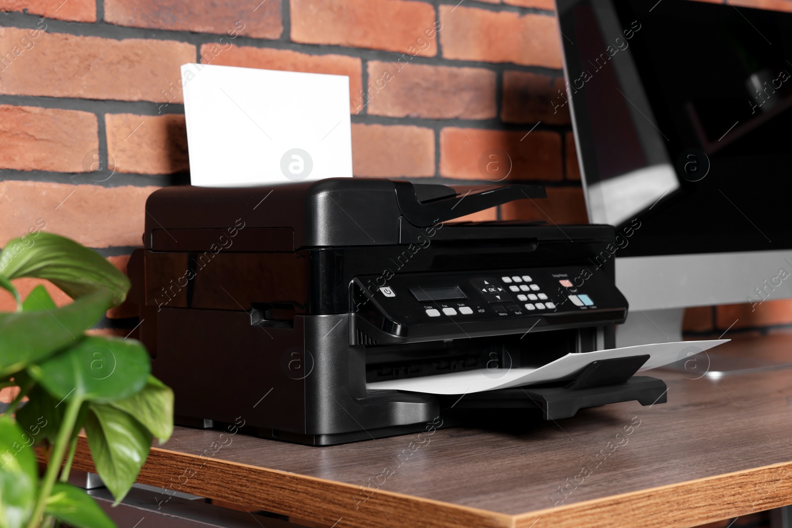 Photo of Modern printer with paper near computer on wooden desk at home