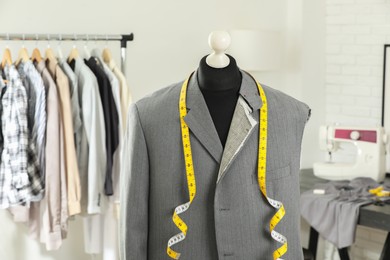 Photo of Mannequin with unfinished jacket and measuring tape in tailor shop
