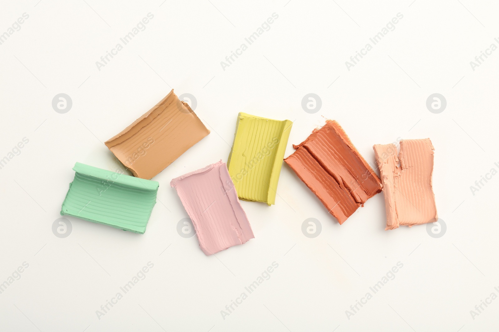 Photo of Samples of different color correcting concealers on white background, top view