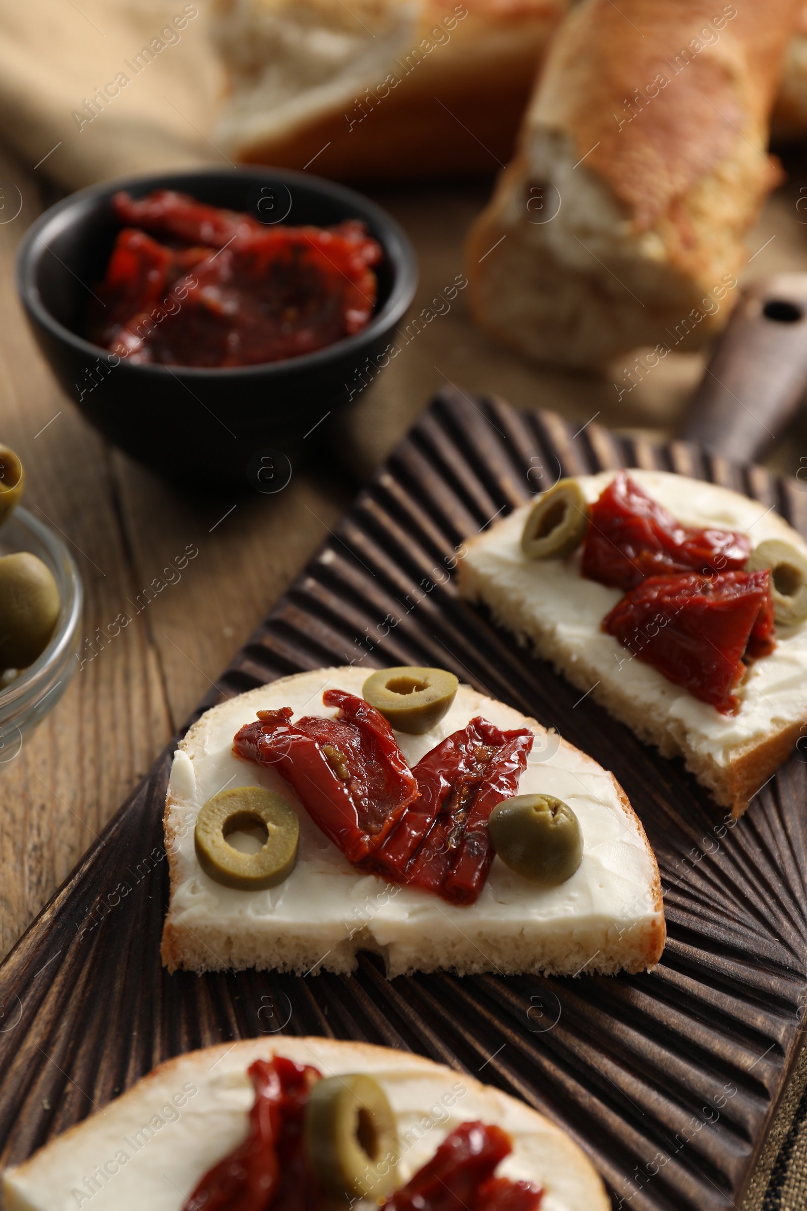 Photo of Delicious bruschettas with ricotta cheese, sun dried tomatoes and olives on table, closeup