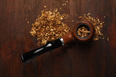 Smoking pipe with tobacco on wooden table, flat lay