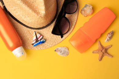 Photo of Flat lay composition with bottles of sunscreen on yellow background