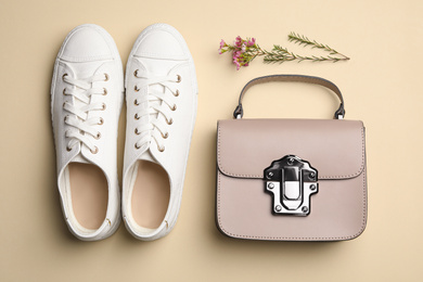 Stylish woman's bag, shoes and flowers on beige background