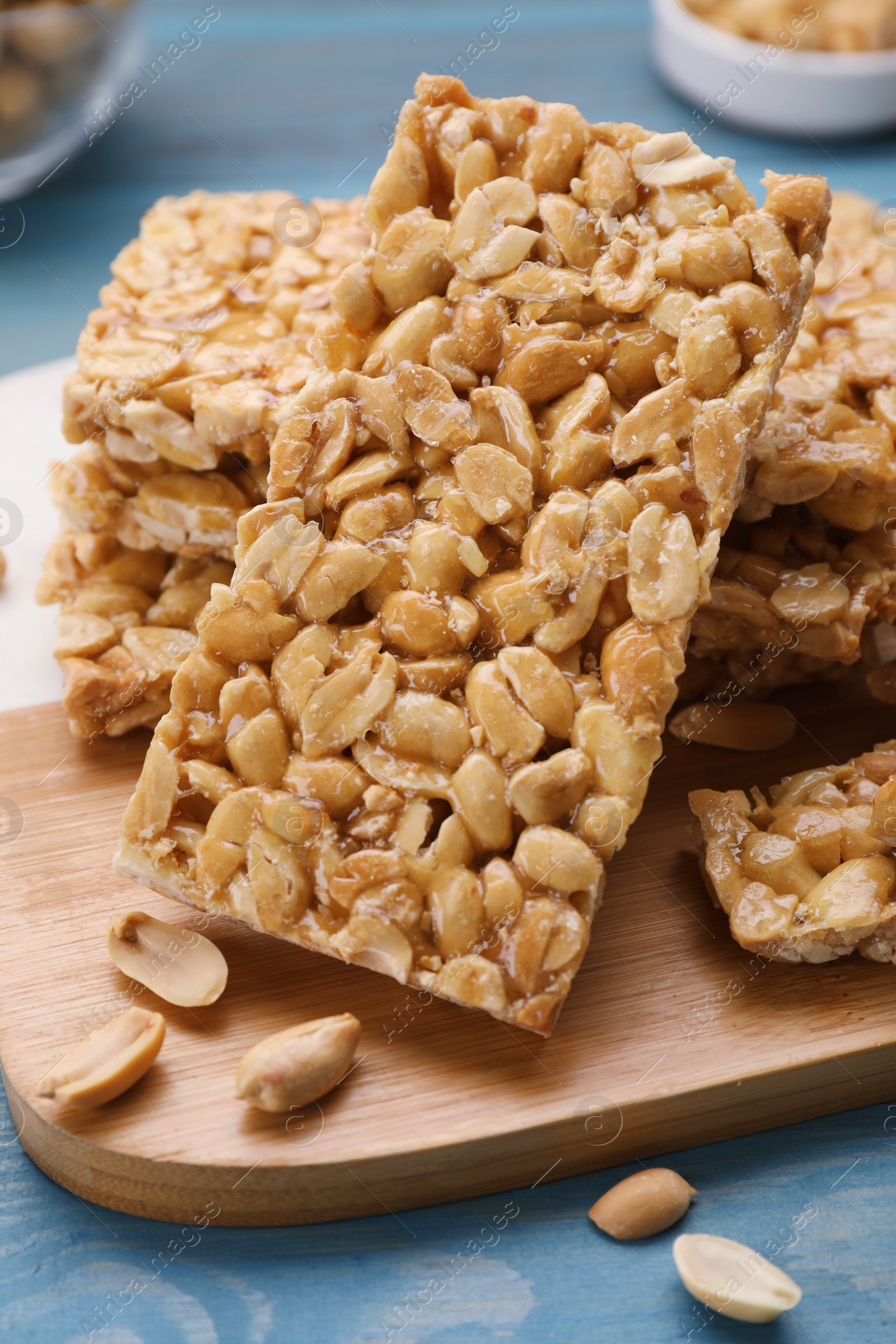 Photo of Delicious peanut bars (kozinaki) on light blue wooden table, closeup