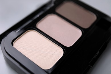 Beautiful eyeshadow palette on light gray background, closeup. Professional cosmetic product