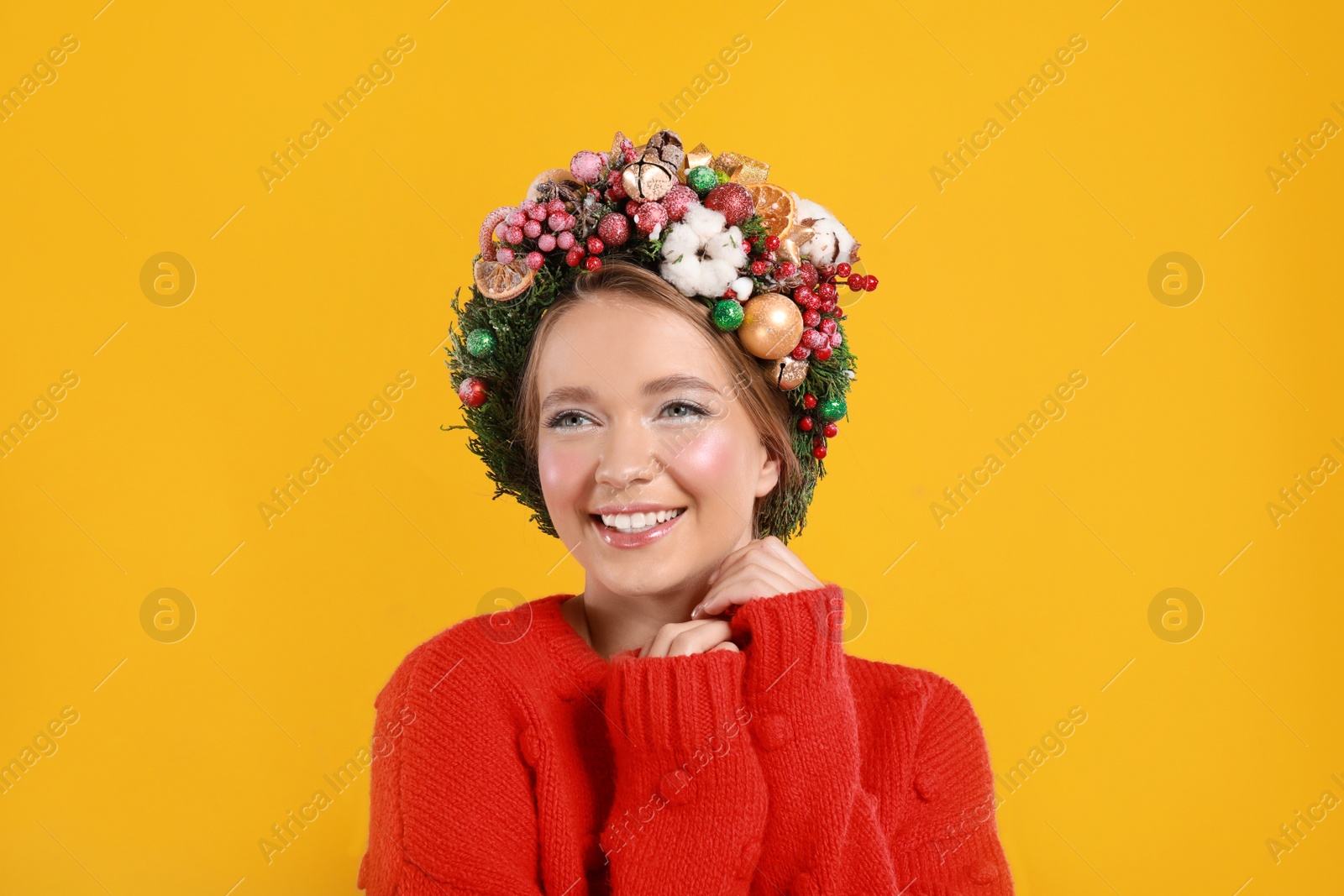 Photo of Beautiful young woman wearing Christmas wreath on yellow background