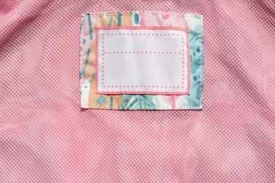 Photo of Clothing label on pink garment, top view