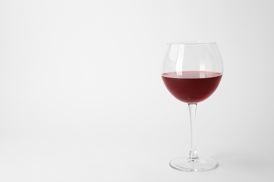 Glass of expensive red wine on light background