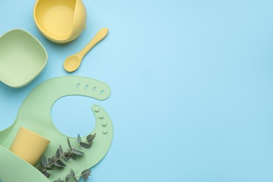 Photo of Flat lay composition with baby feeding accessories and bib on light blue background, space for text