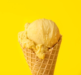 Delicious ice cream in waffle cone on yellow background, closeup