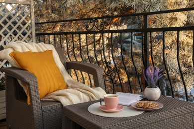 Photo of Cup with tasty cocoa, cookies and book on rattan table at balcony